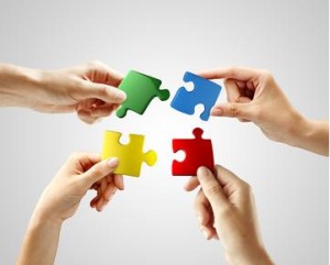 Hands and puzzle on gray background. Teamwork solving a puzzle